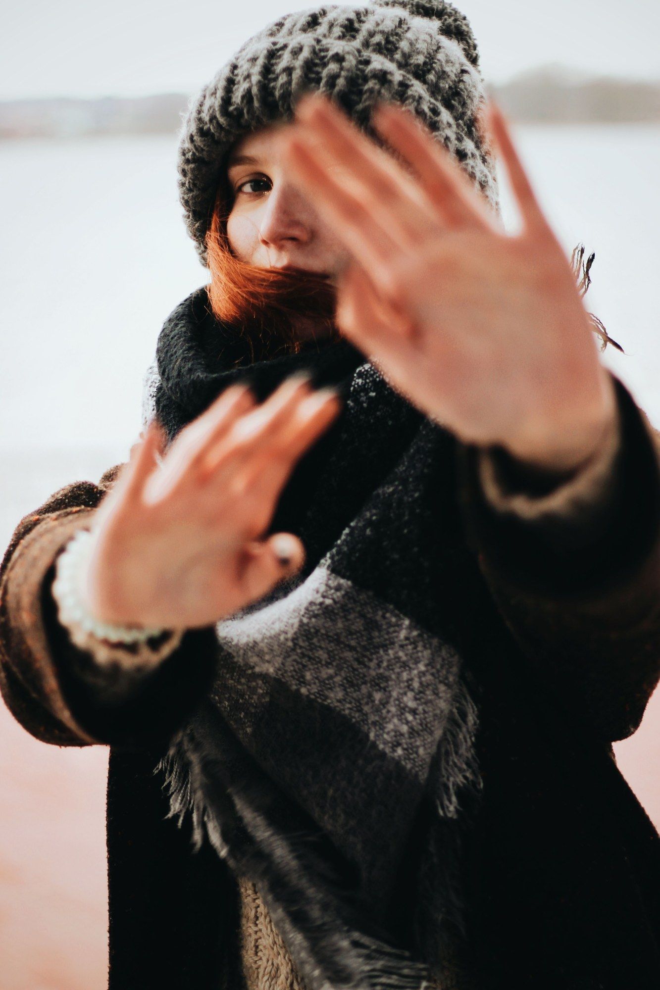 Mujer con gorro y bufanda de lana tapándose la cara en invierno
